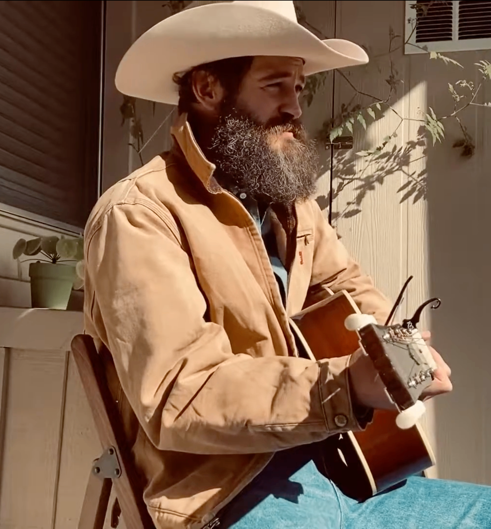 Matt Steinfeld in a cowboy hat playing guitar